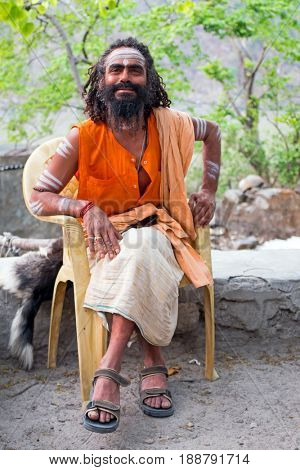 LAXMAN JHULA, INDIA - APRIL 20, 2017: A Hindu sadhu sitting in the streets in Laxman Jhula on the 20th april 2017 in India Asia
