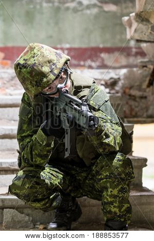 Portrait of armed woman with camouflage. Young female soldier observe with firearm. Child soldier with gun in war hearth house ruins background. Military army people concept