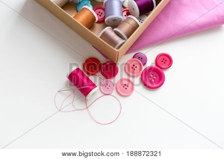 needlework, craft, sewing and tailoring concept - box with thread spools and buttons on table