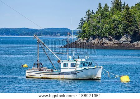 A hard working lobster boat lays at anchor in a small harbor in the Down East region of Maine.