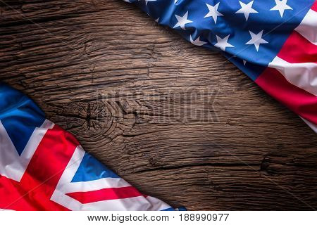 Flags of american and united kingdom on rustic oak board. UK and USA flags together diagonally.