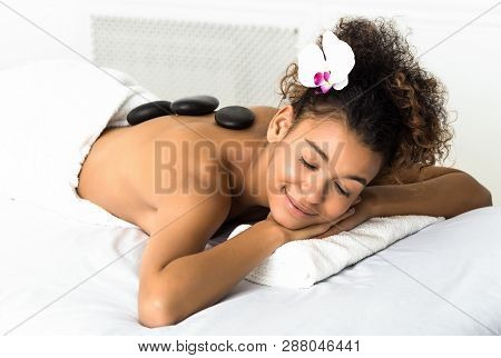 Stone Massage. Woman Relaxing At Spa Salon With Closed Eyes