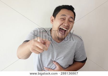 Portrait Of Funny Asian Man Laughing Hard And Pointing Forward, Bully Expression, Close Up Head Shot