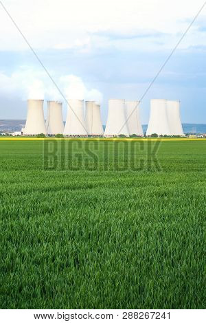 Green Fields With Cooling Towers Of Nuclear Power Plant In Background