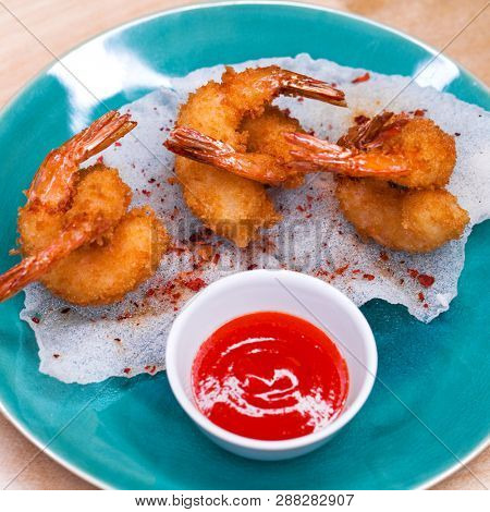 Restaurant dish. Deep fried king prawns with spicy sauce on a blue plate