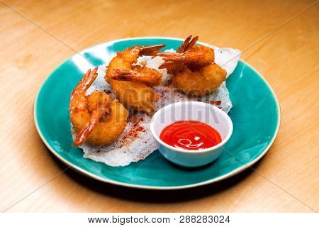 Restaurant dish. Deep fried king prawns with spicy sauce on a blue plate