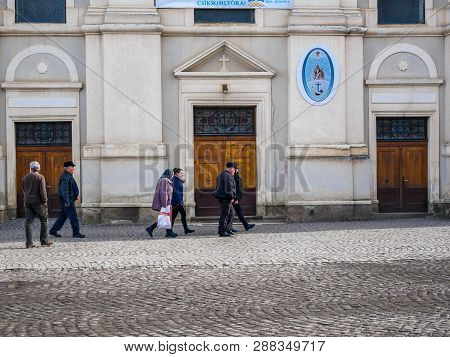 Sumuleu Ciuc, Romania- 09 March 2019: People Walking In Front Of The Local Catholic Church.
