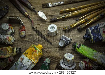 Old Paint Tubes And Brushes On Wooden Background