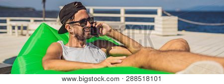 Young Man Enjoying Leisure, Lying On The Air Sofa Lamzac, Near The Sea Banner, Long Format