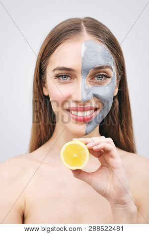 Attractive Caucasian Woman With Facial Mask On Face Holds Citrus Fruit On Her Hand On White Backgrou