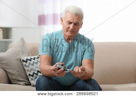 Senior Man Using Digital Glucometer At Home. Diabetes Control