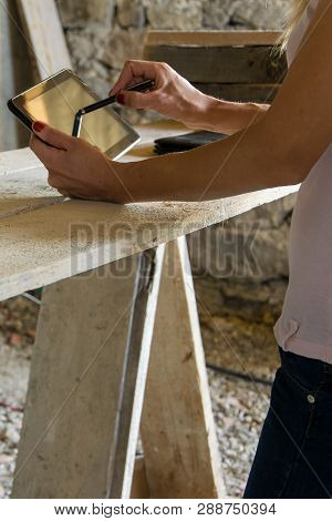 Crop View Of Female Young Adult With Portable Information Device In Hand Makes A Project  In A Carpe