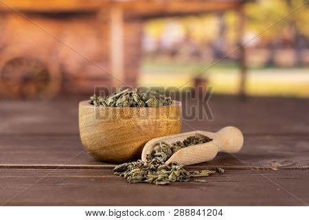Lot Of Pieces Of Dry Green Tea In A Scoop With Wooden Bowl In A Country Yard