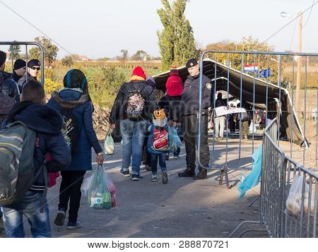 Berkasovo, Serbia - October 31, 2015: Croatian Policeman Looking At Refugees, Mainly Children, Cross