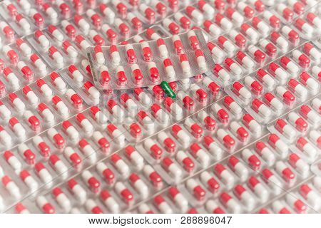 Green Capsule On The Background Of Red And White Capsules In Blisters