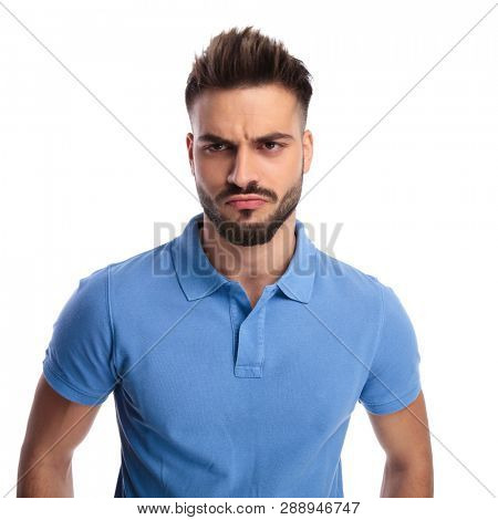 Young imature  man wearing a light blue polo frowning while looking at a side on a light background