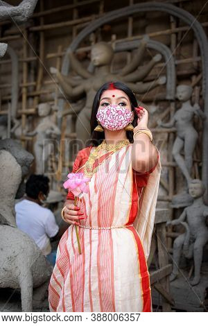 Portrait Of Beautiful Indian Girl Standing In Front Of Durga Idol Wearing Traditional Indian Saree, 
