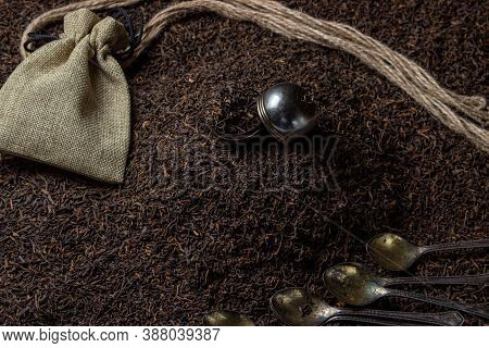 Leaf Tea. A Lot Of Loose Tea. Teaspoons, A Pouch And A Tea Ball Lay On Loose Tea