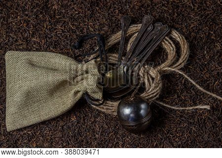 Leaf Tea. A Lot Of Loose Tea. Teaspoons, A Pouch And A Tea Ball Lay On Loose Tea