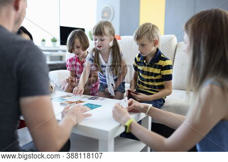 Team Of Three Children And Team Of Three Adults Play Board Games At Home. Deck Of Cards And Playing 