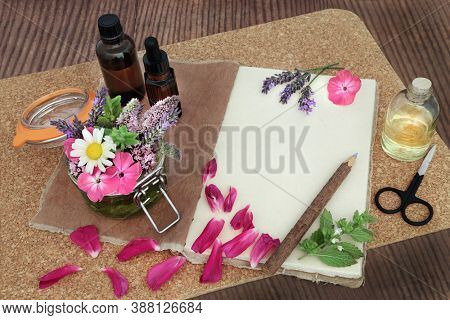 Natural herbal medicine preparation with flowers and herbs steeping in a jar with oil & loose for aromatherapy essential oil with tincture bottles and hemp notebook. Naturopathic health care concept.