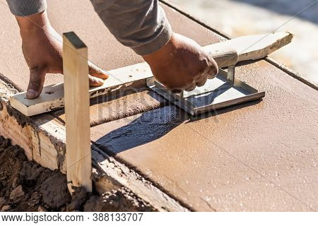 Construction Worker Using Hand Groover On Wet Cement Forming Coping Around New Pool.