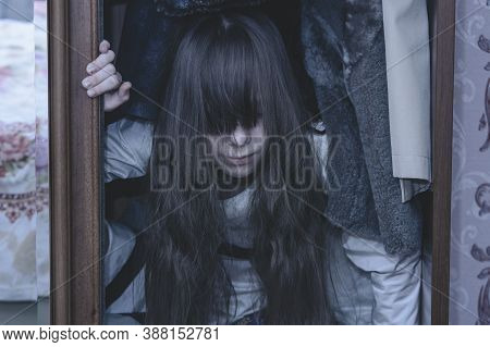 Mad Scary Girl In Cupboard At Dark Night. Horror Background With Child Possessed By Devil. Demon Pos