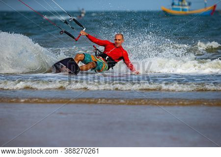 Kitesurfing on the waves of the sea in Mui Ne beach, Phan Thiet, Binh Thuan, Vietnam. Kitesurfing, Kiteboarding action photos. Kitesurf In Action 