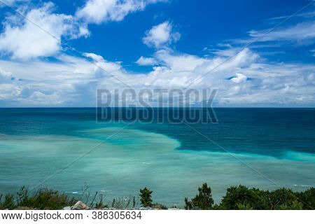 Blue Sea Against The Cloud Sky, The View From The Cliff. The Water Is Multicolored
