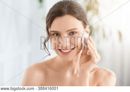 Smiling Pretty Young Woman Cleaning Her Face, Using Cotton Pads And Cleansing Product, Closeup. Youn
