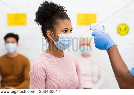 Medical Worker Doing Temperature Screening For Patient Teen Girl Measuring Fever Before Doctors Appo