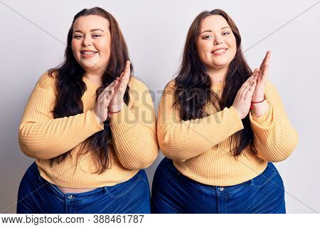 Young plus size twins wearing casual clothes clapping and applauding happy and joyful, smiling proud hands together 