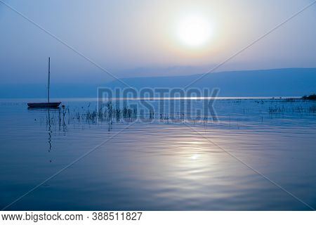 Sunrise Over The Lake. Boat Floating On The Calm Water Under Amazing Sunset.