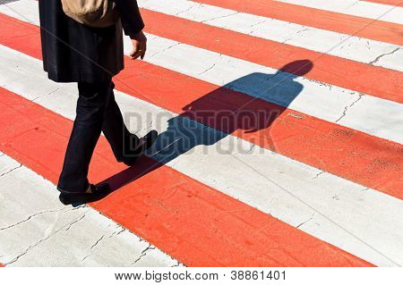 a woman walks on a pedestrian crossing. shadows on a protection path.