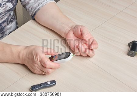 A Senior Woman With Diabetes Checks Her Blood Sugar Level With A Glucose Meter, A Drop Of Blood On H