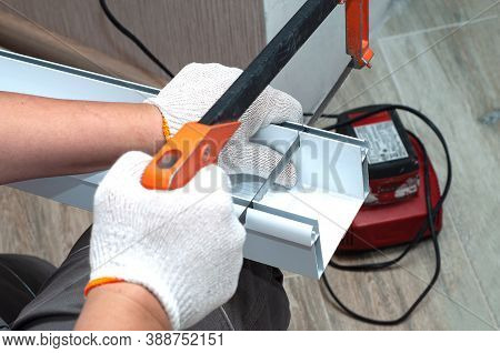 Workman In Gloves Cuts Metal Profile For Led Lamp For Stretching Ceiling. Close-up View