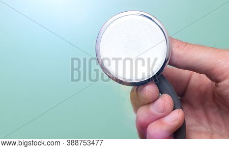 Female Hand Holds A Stethoscope On A Blue Background. Concept Doctor, Doctor's Appointment, Virus, T