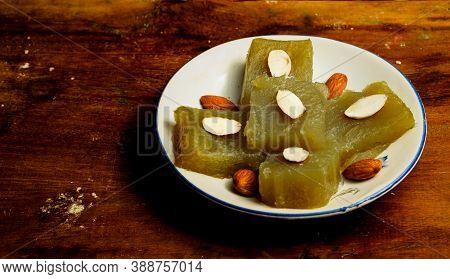 Indian Homemade Dessert Wheat Halwa Garnished With Badam On A Colorful Background