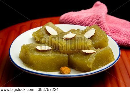 Indian Homemade Dessert Wheat Halwa Garnished With Badam On A Colorful Background