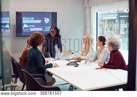 Young Businesswoman Leading Creative Meeting Of Women Collaborating Around Table In Modern Office