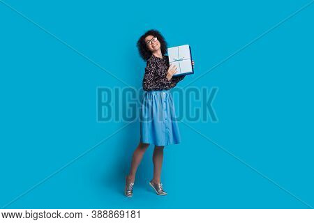 Monochrome Photo Of A Caucasian Woman With Curly Hair And Glasses Posing In A Dress On A Blue Wall H