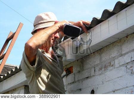 Kyiv, Ukraine - October  13, 2020:  Roof Guttering Installation: A Building Contractor Is Fixing A P