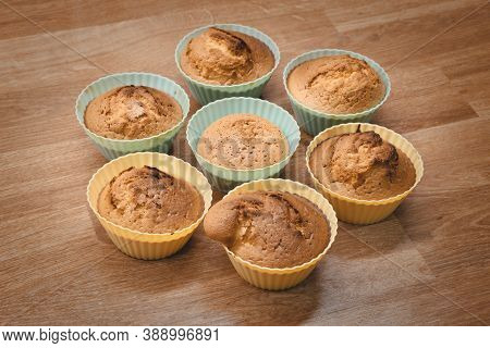 Group Of Cupcakes In Silicone Forms On The Wooden Table. Just Baked Cupcakes. Home Coocking Concept.