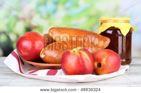 Empanadillas al horno frescos con mermelada de frutas, en la mesa de madera, sobre fondo brillante