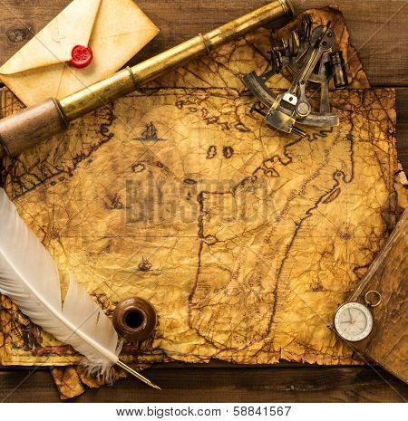 Sextant, spyglass and envelope on vintage map over wooden background 