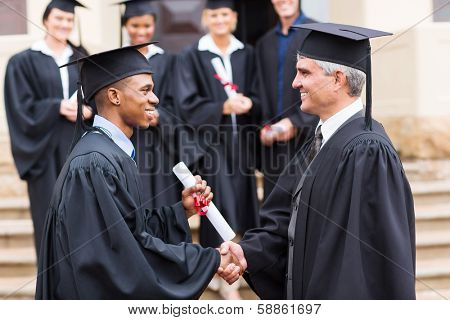 happy african male graduate handshaking with dean