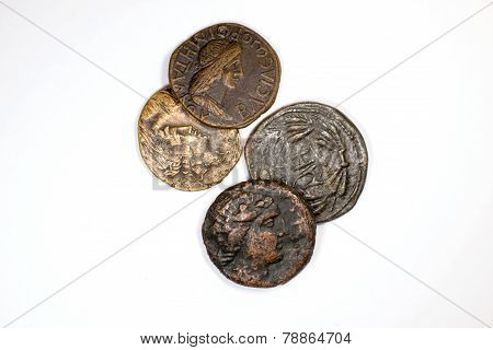 Four Old Coins With Portraits Of Emperors On A White Background
