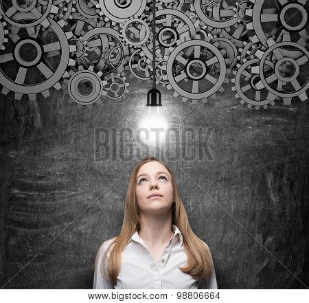 Young Charming Business Woman Is Looking At The Light Bulb As A Concept Of Innovative Business Ideas