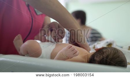 Newborn baby in maternity hospital - nurse is swaddling the infant, close up