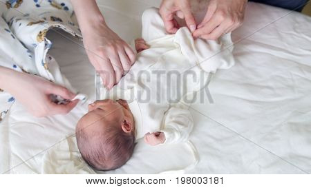 Newborn baby, mother and nurse - swaddling the infant, close up